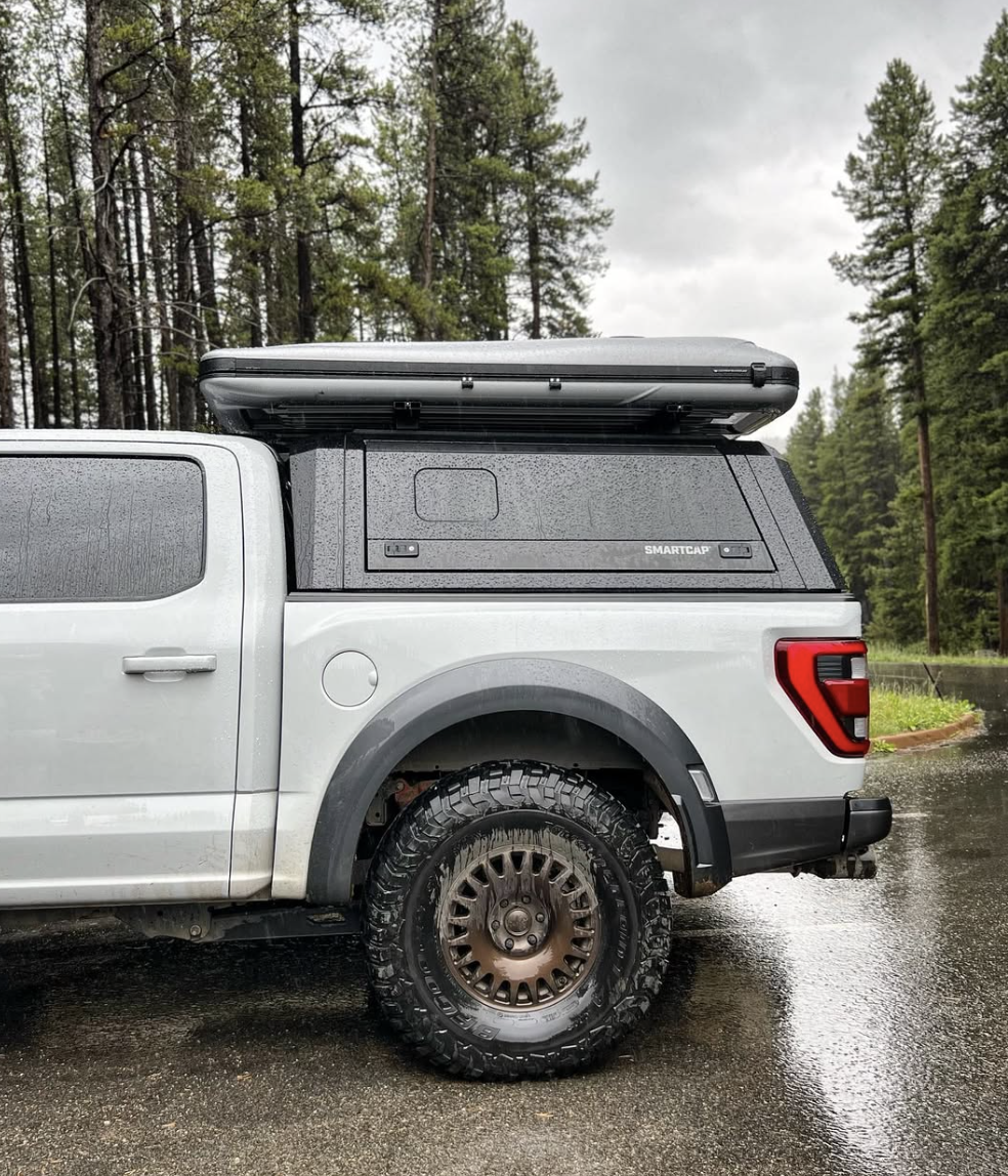 Grey truck with a truck cap topper and roof top tent