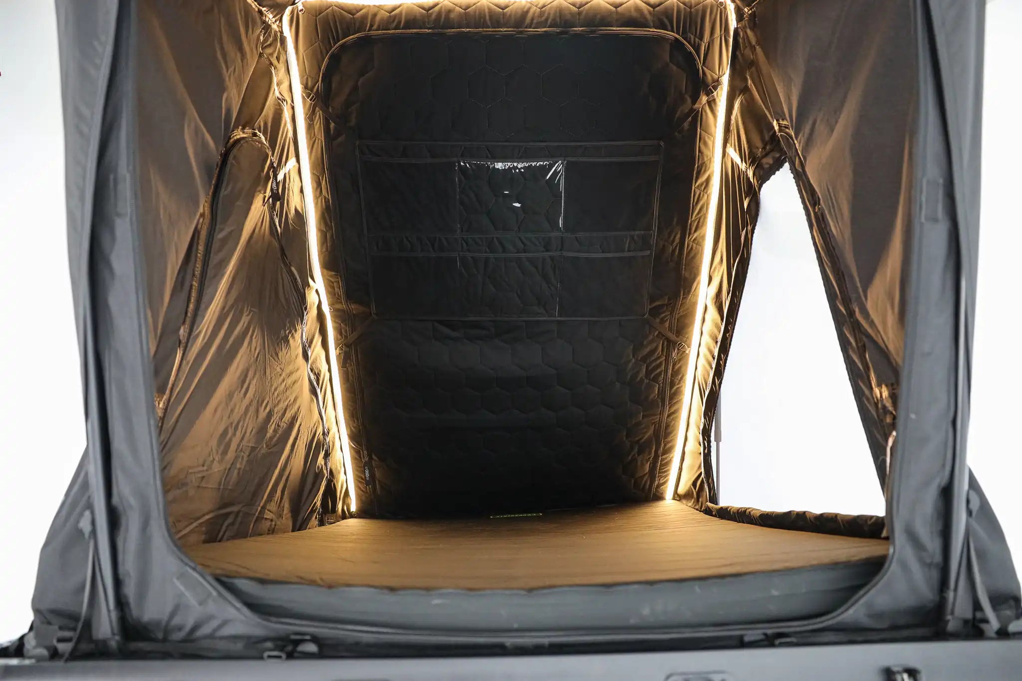 Car trunk with a portable tent setup inside, illuminated by a light source.