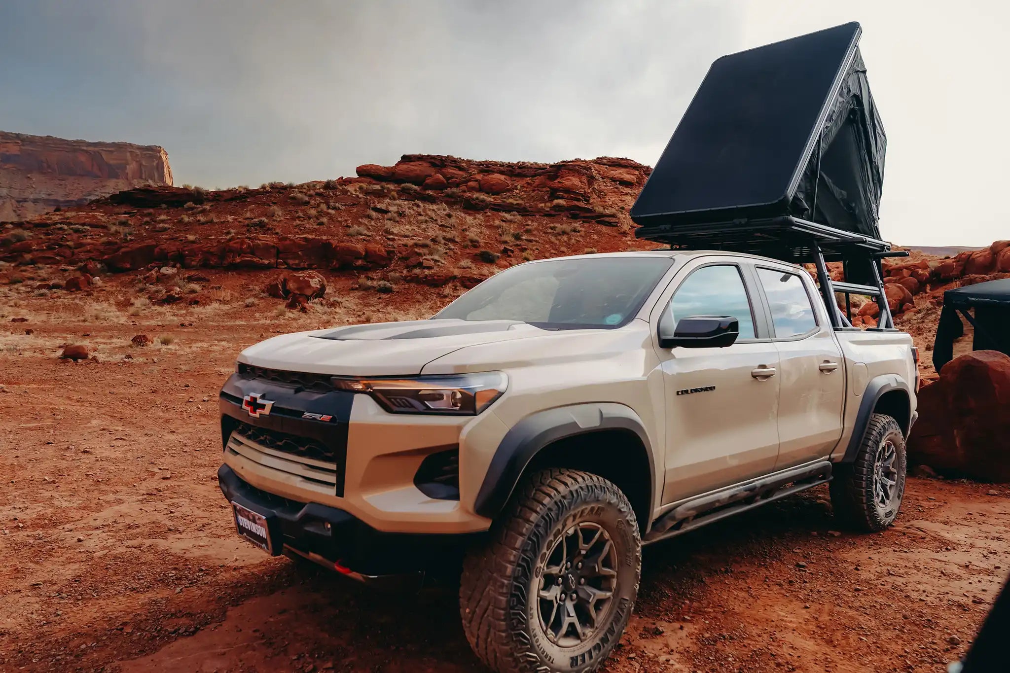 Beige truck with a roof tent in a desert landscape