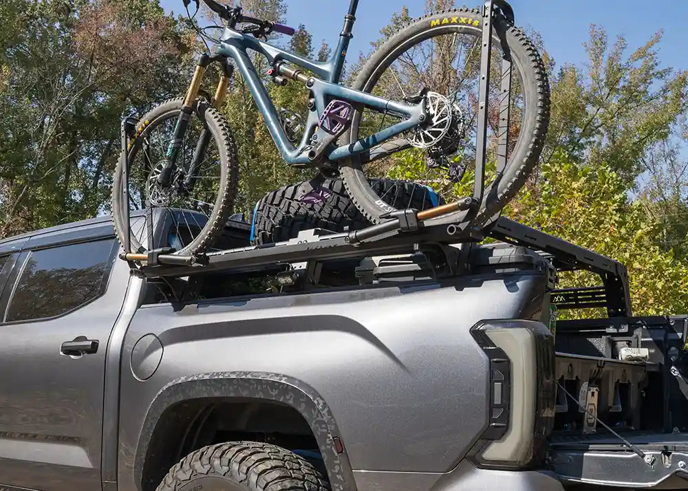 Bicycle on a roof rack of a silver SUV with trees in the background