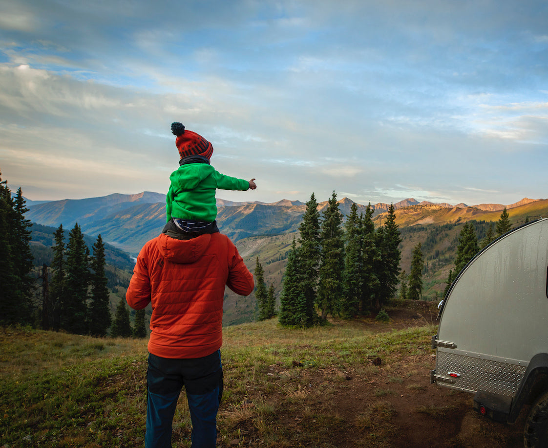 boy in green coat  on dads shoulders in mountains
