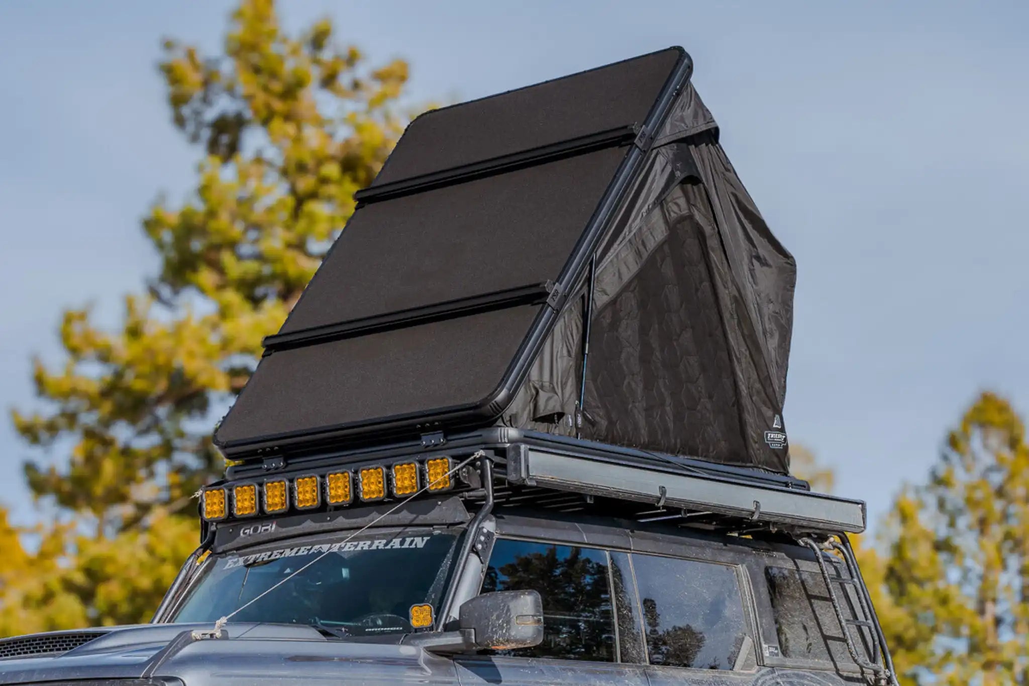 Roof top tent on a vehicle with trees in the background