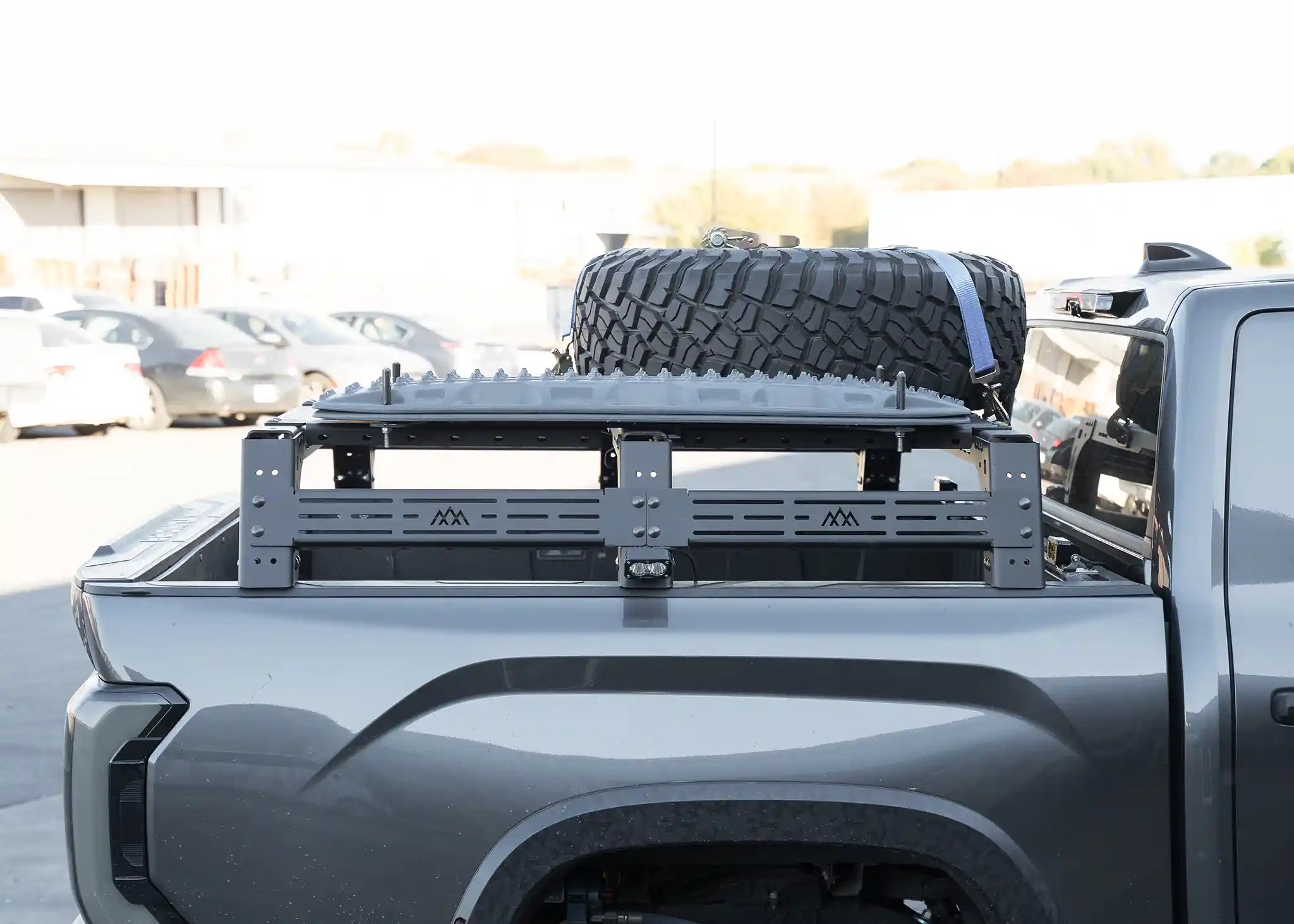 Gray truck bed with a tire and rack in an outdoor setting