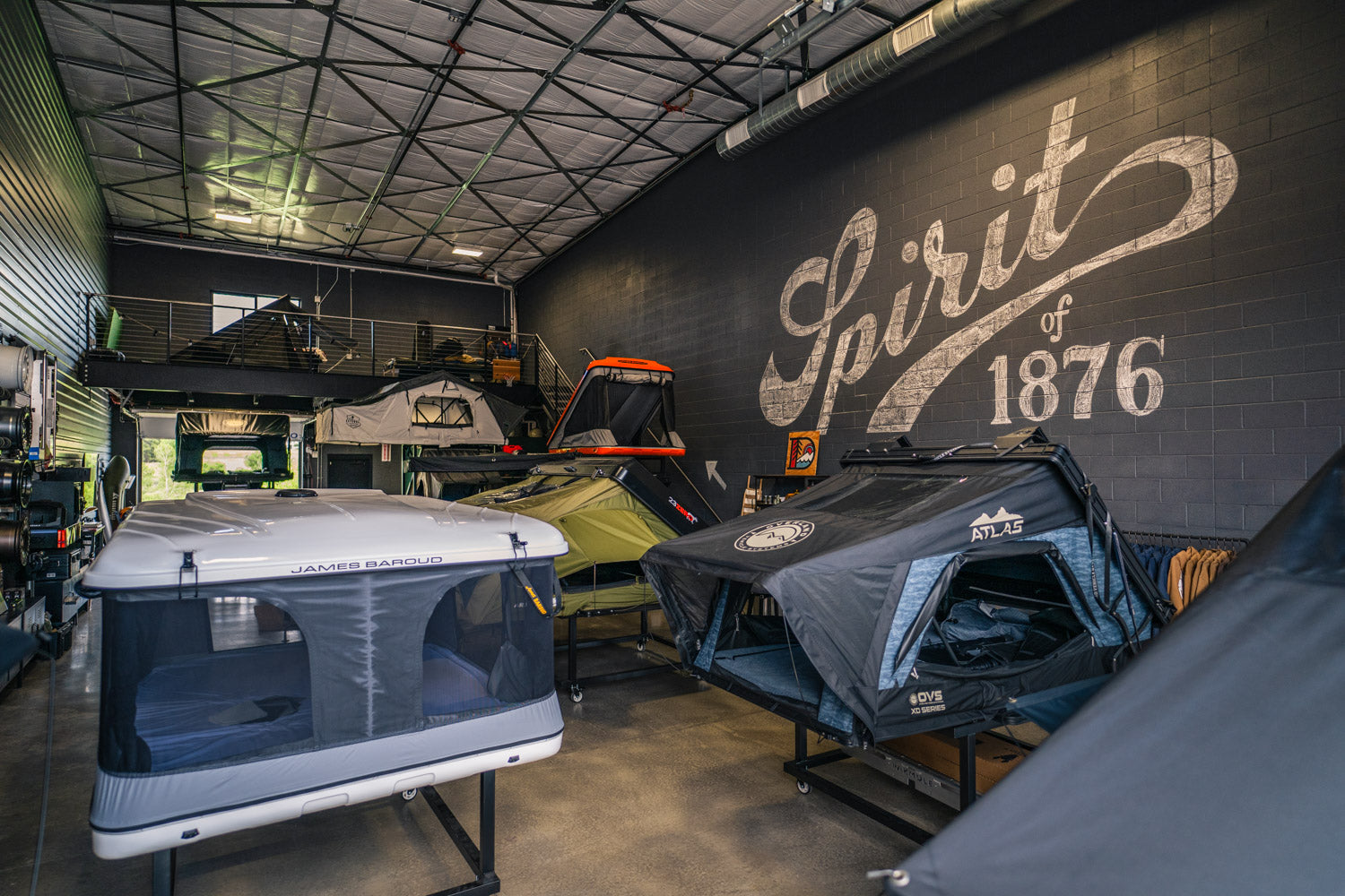Camper vans on display in a showroom with 'Spirit of 1876' branding.
