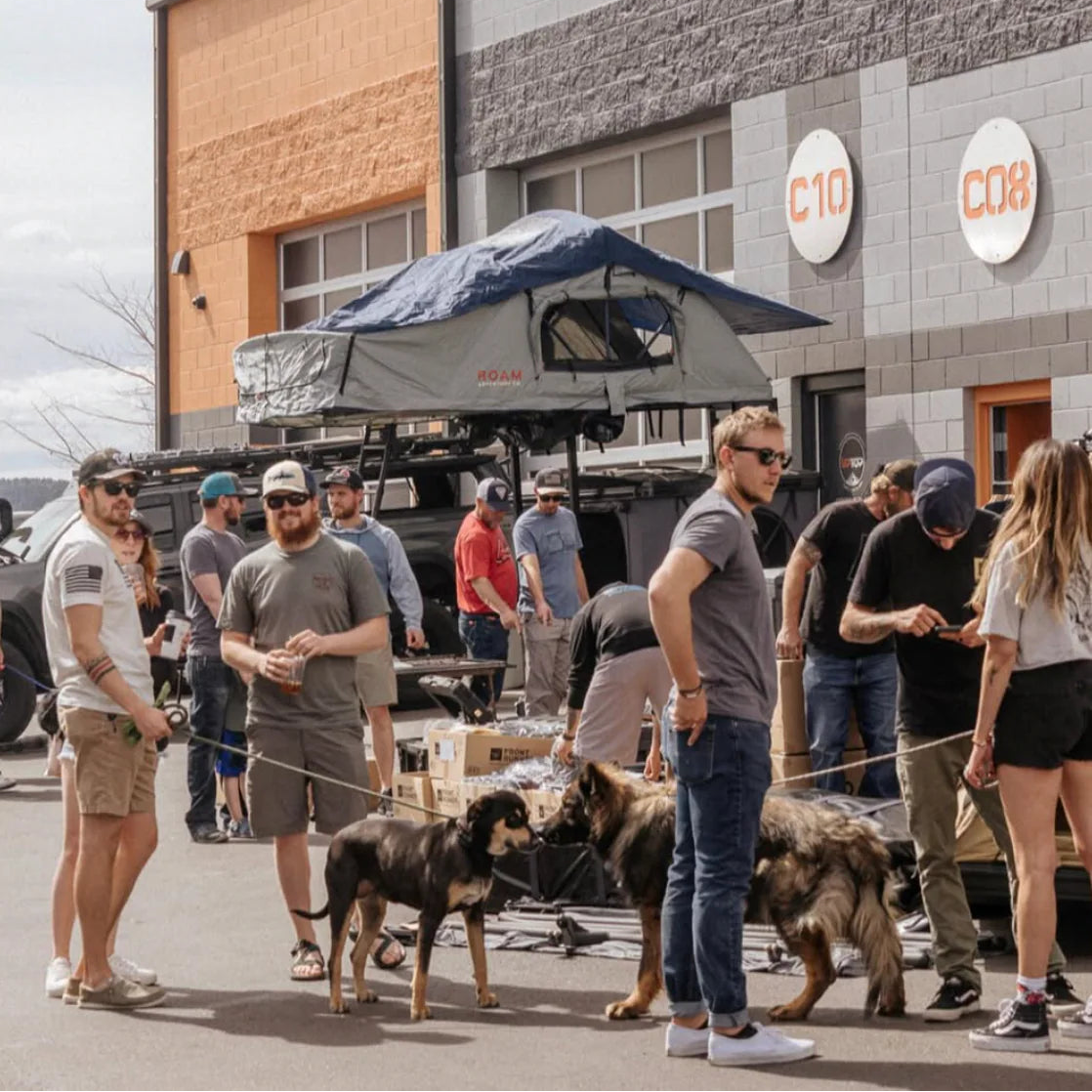 Group of people with dogs in front of a building with 'C10' branding