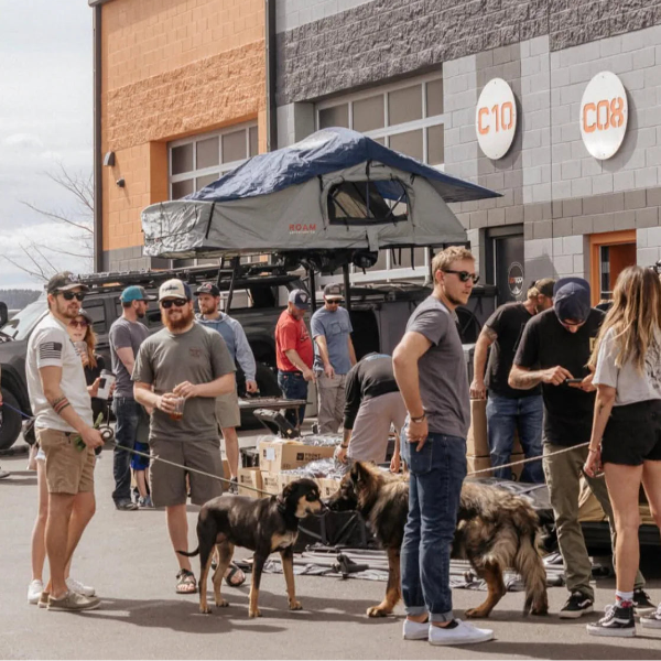Group of people with dogs in front of a building with 'C10' branding