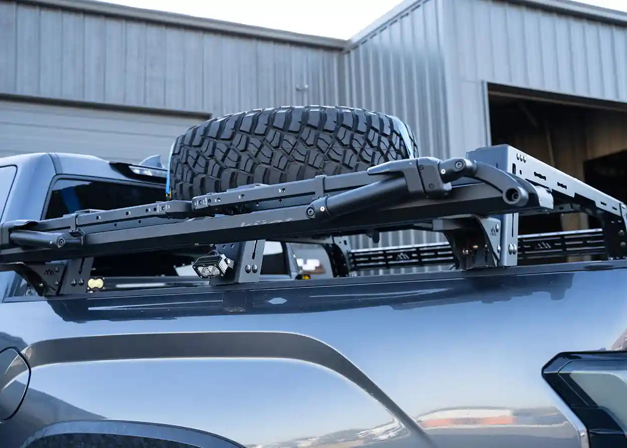 Roof rack system on a vehicle with a tire mounted on it, outdoors.