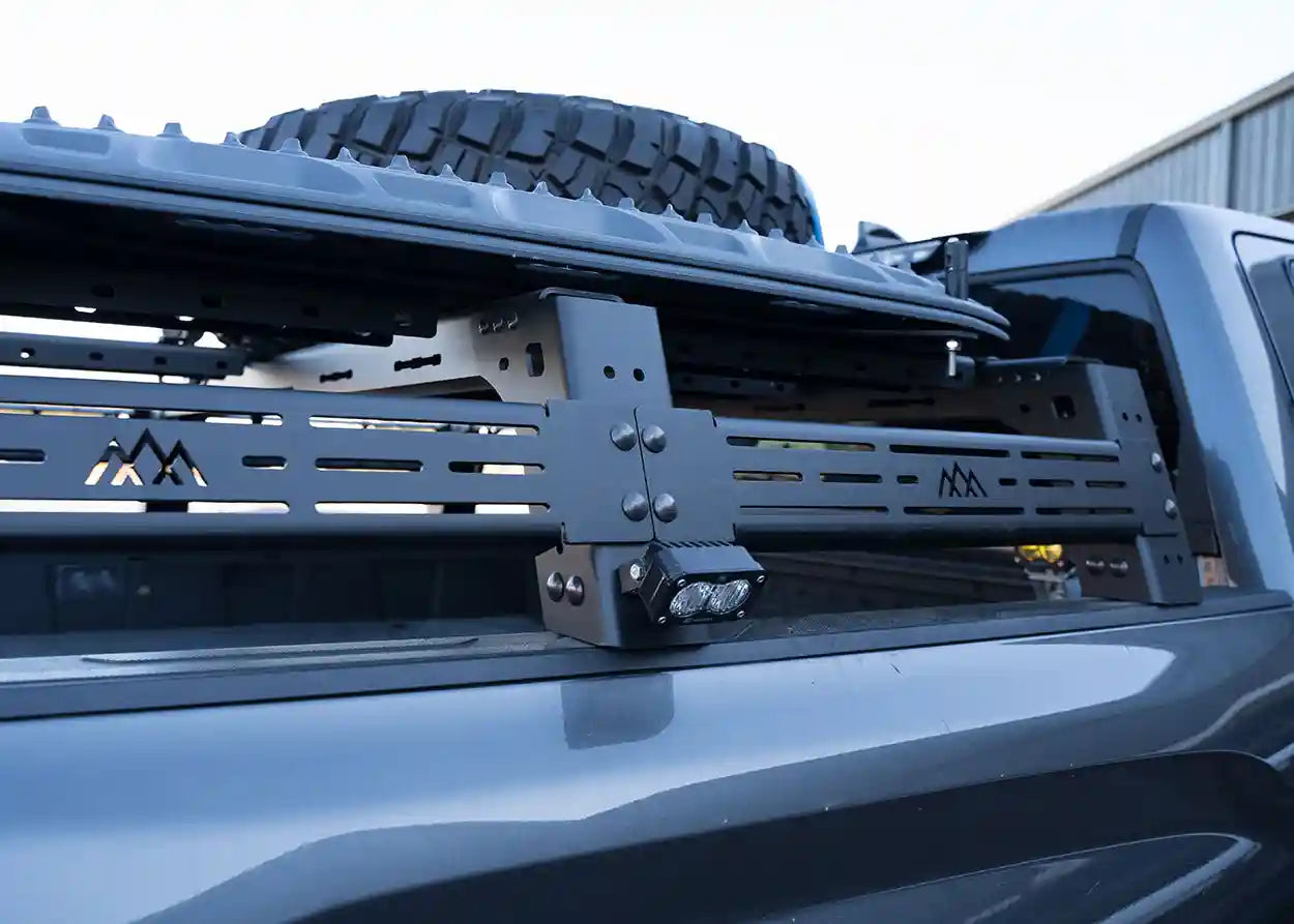 Close-up of a truck bed rack system on a vehicle with a tire partially visible.