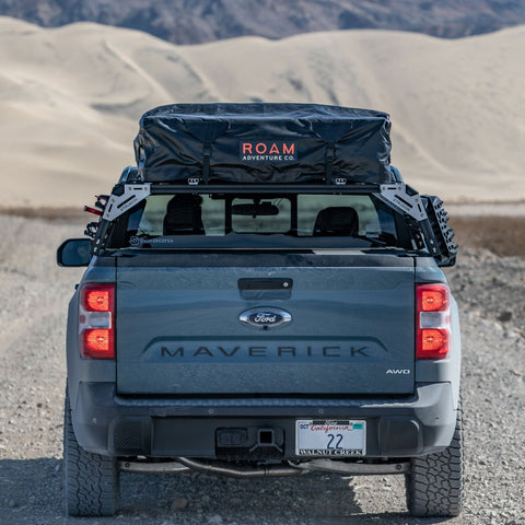 Back of Ford Maverick FX4 with overland bed rack, tonneau cover, and molle panels, loaded with ROAM RTT and traction boards