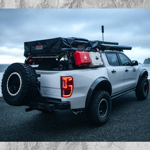 Ford Ranger with extrusion bed rack Roof top tent, off-road lights, awning, cases, Rotopax, WeBoost antenna, and overlanding gear.