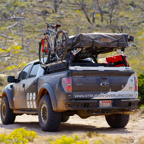 Gen 1 Ford Raptor Xtrusion Overland Bed Rack with Rotopaxâ€™s mounted, Molle panels, Mountain Bike, awning, and Roof top tent.